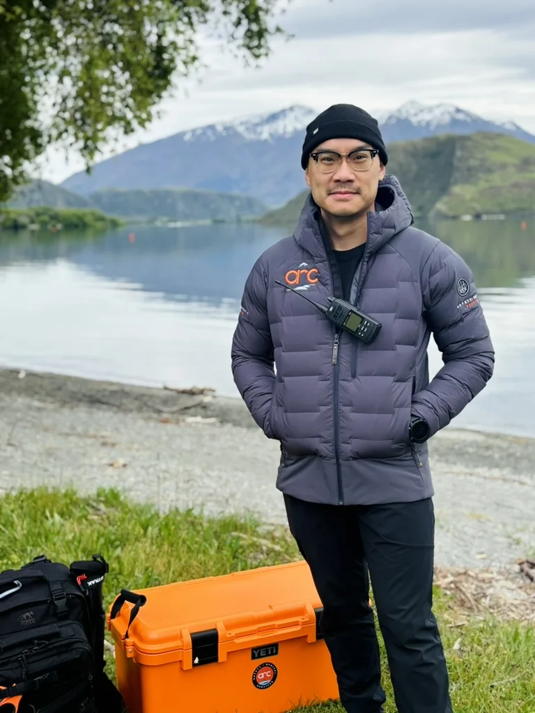 Arc medical team member beside a lake with mountains in the background